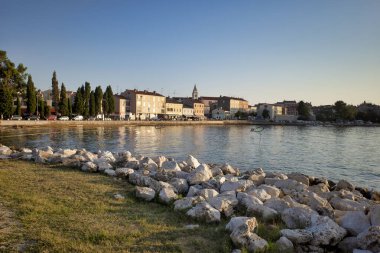 Adriyatik Denizi tatil köyü. Şehir plajları, bitki örtüsü ve binalar. Taştan bir sahili olan deniz burnu.