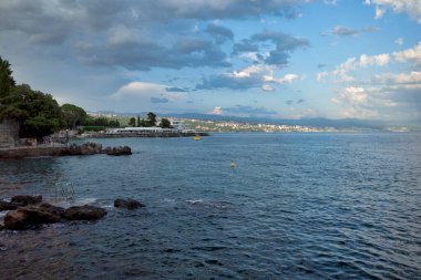 Rijeka, Hırvatistan - 11 Ağustos 2021: Adriyatik Denizi üzerinde tatil yeri. Hırvatistan 'da şehir plajları, bitki örtüsü ve binalar. Taştan bir sahili olan deniz burnu.