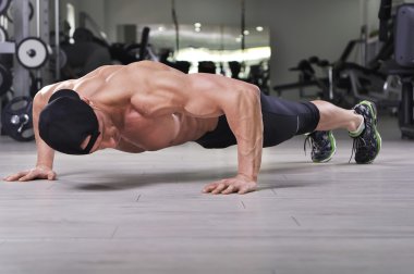Push up salonunda gerçekleştirme yakışıklı güçlü atletik bir adam. Mükemmel sırt, omuz, pazı, triceps ve göğüs ile güçlü vücut geliştirmeci.