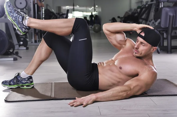 Bonito homem atlético poderoso realizando crunches. Forte fisiculturista com abdominais perfeitos, peito e bíceps . — Fotografia de Stock