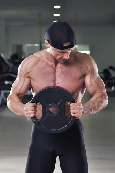 Bonito homem atlético poderoso realizando exercício estático com peso. Forte fisiculturista com perfeito, ombros, braços e peito . — Fotografia de Stock