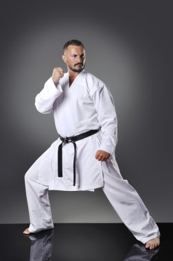Yakışıklı genç erkek karate kata gri arka plan üzerinde yapıyor