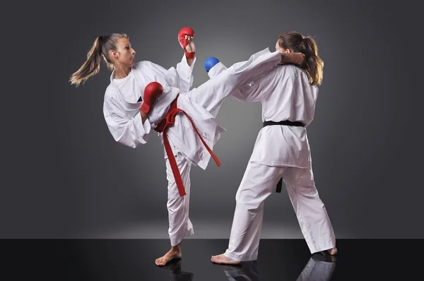 Dvě samice mladé karate bojuje na šedém pozadí — Stock fotografie