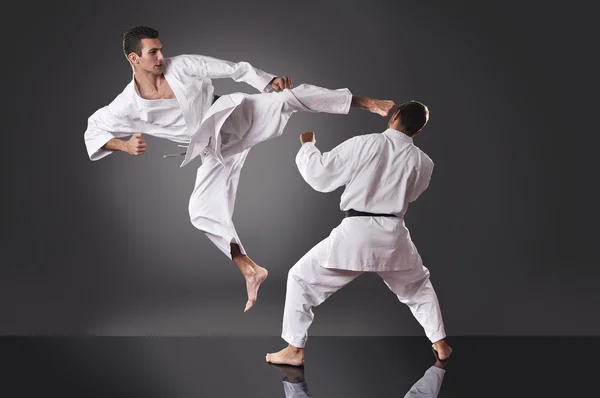 Två stilig unga manliga karate slåss på den grå bakgrunden — Stockfoto