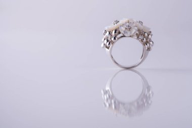 Gri arka planda inci ve zirkon bulunan lüks altın bir yüzük. Beyaz altın