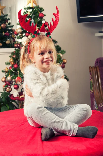 Schönes Kleines Mädchen Mit Hörnern Das Neben Dem Weihnachtsbaum Sitzt — Stockfoto