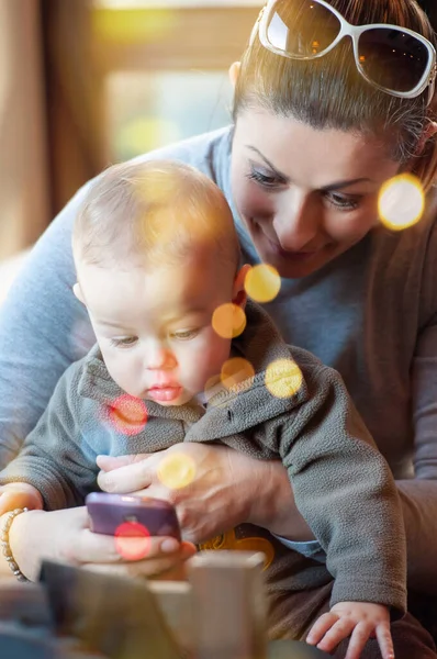 Feliz Madre Sosteniendo Hijo Regazo Mostrando Algo Contenido Teléfono Celular — Foto de Stock