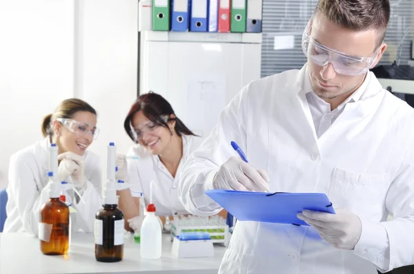 Attractive young PhD student scientist writing a note in laborat — Stock Photo, Image