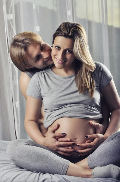 Gelukkige paar holding zwangere buik en glimlach — Stockfoto