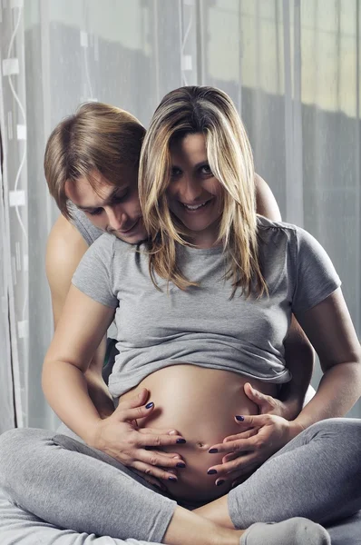 Gelukkige paar holding zwangere buik en glimlach — Stockfoto