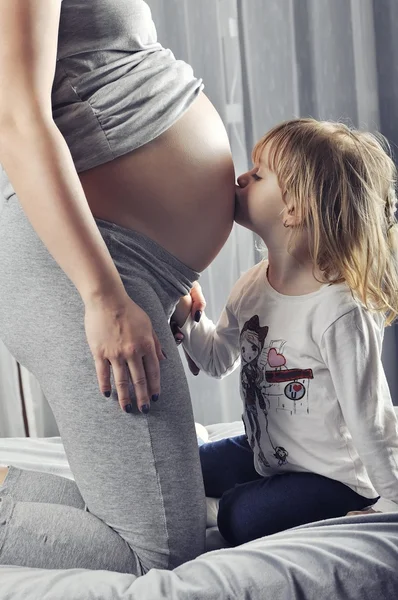 美しい少女は、彼女の胎児の弟をキス — ストック写真