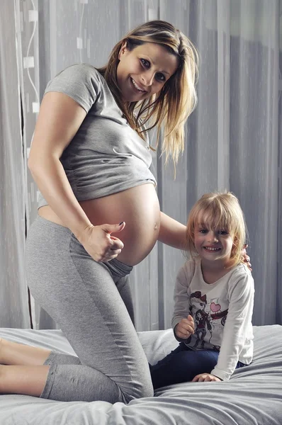 Mãe e filha feliz mostrando o polegar para cima por causa da gravidez — Fotografia de Stock