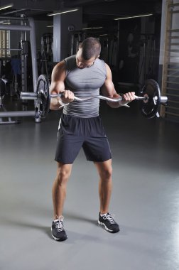 Pazı egzersiz yaparak kusursuz bir beden ile ayakta pozisyonda yakışıklı kaslı erkek modeli