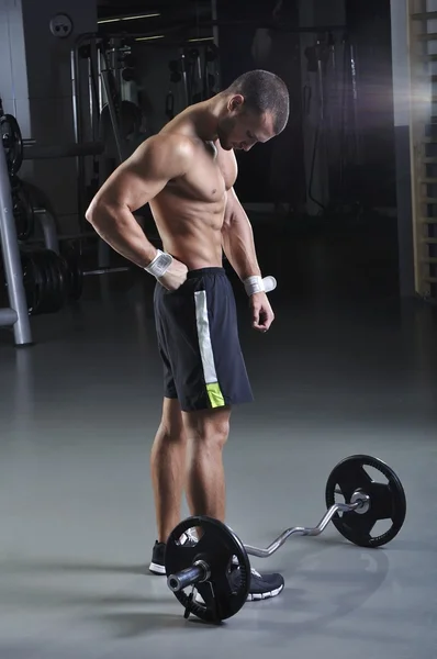 Modelo masculino muscular bonito com corpo perfeito posando ao lado de Barbell — Fotografia de Stock