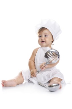 Funny adorable baby boy chef sitting and playing with kitchen equipment