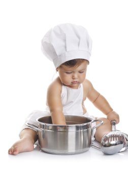 Funny adorable baby boy chef sitting and playing with kitchen equipment