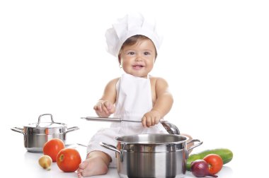 Funny adorable baby boy chef sitting and playing with kitchen equipment