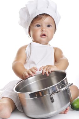 Funny adorable baby boy chef sitting and playing with kitchen equipment