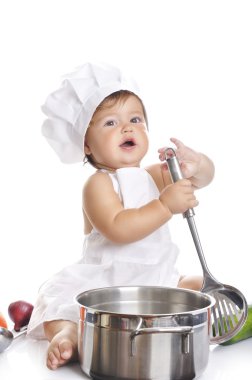 Funny adorable baby boy chef sitting and playing with kitchen equipment