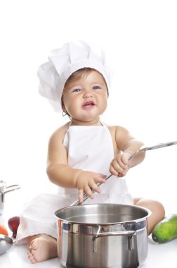 Funny adorable baby boy chef sitting and playing with kitchen equipment