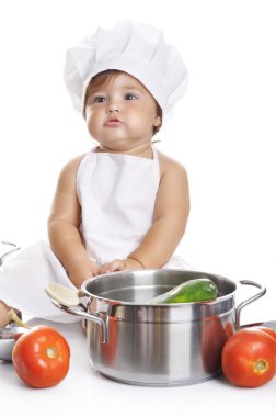 Funny adorable baby boy chef sitting and playing with kitchen equipment