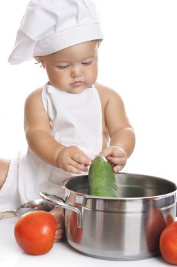 Funny adorable baby boy chef sitting and playing with kitchen equipment