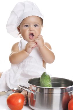 Funny adorable baby boy chef sitting and playing with kitchen equipment