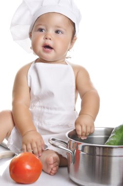 Funny adorable baby boy chef sitting and playing with kitchen equipment
