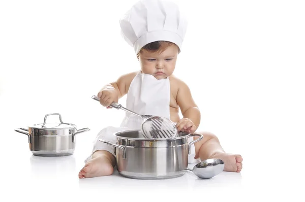 Engraçado adorável bebê menino chef sentado e brincando com equipamentos de cozinha — Fotografia de Stock