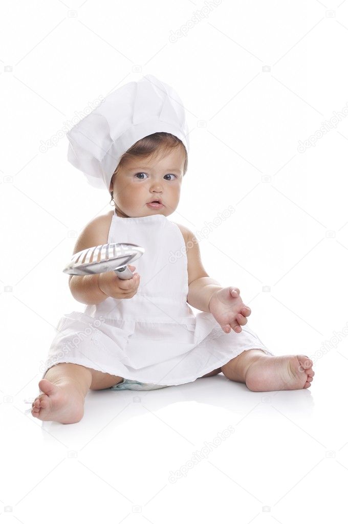 Funny adorable baby boy chef sitting and playing with kitchen equipment