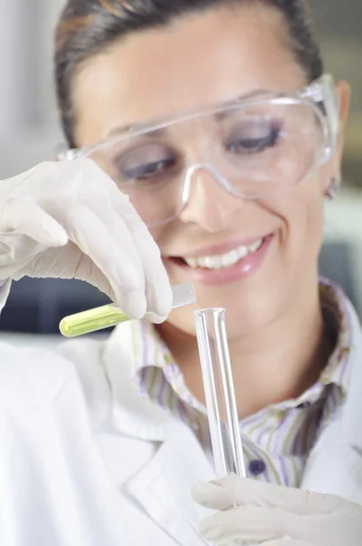 Attractive young PhD student scientist observing the green indicator color shift after the solution destillation in chemical laboratory — Stock Photo, Image