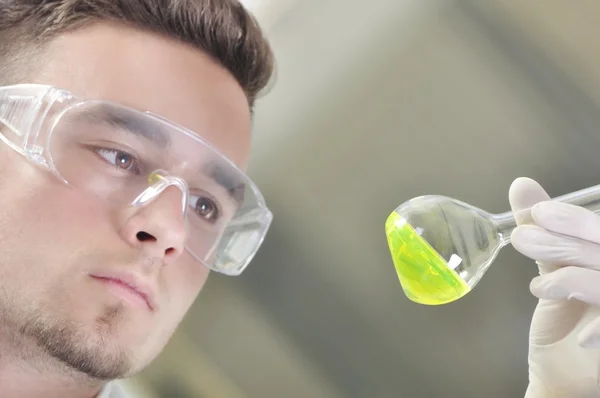 Jeune doctorant scientifique attrayant observant le changement de couleur de l'indicateur vert après la distillation de la solution en laboratoire chimique — Photo