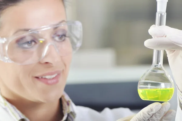 Attractive young PhD student scientist observing the green indicator color shift after the solution destillation in chemical laboratory — Stock Photo, Image