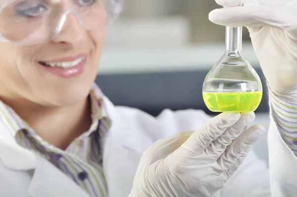 Jeune doctorant scientifique attrayant observant le changement de couleur de l'indicateur vert après la distillation de la solution en laboratoire chimique — Photo