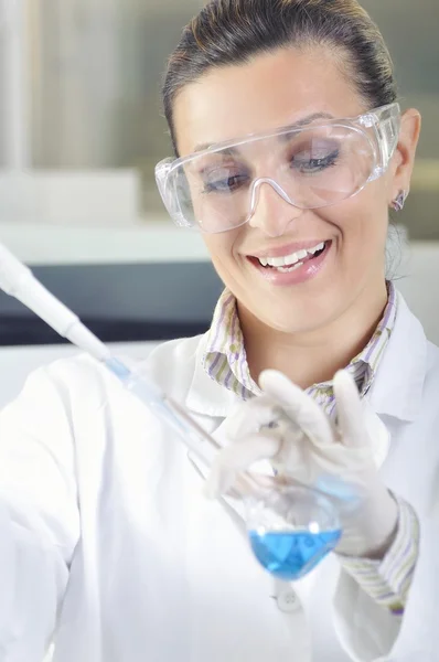 Attractive young PhD student scientist observing the blue indicator color shift after the solution destillation in chemical laboratory — Stock Photo, Image