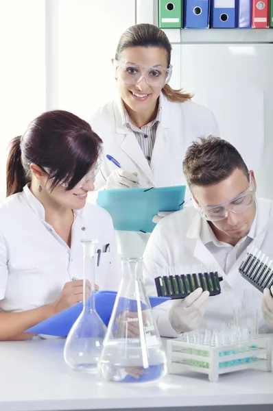 Jovens cientistas estudantes de doutorado atraentes observando a mudança de cor indicador azul, amarelo e verde após a destilação da solução em laboratório químico — Fotografia de Stock