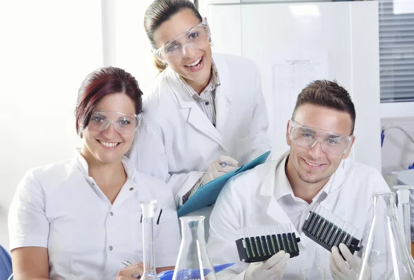 Attractive young PhD students scientists  observing the blue, yellow and green indicator color shift after the solution destillation in chemical laboratory — Stock Photo, Image