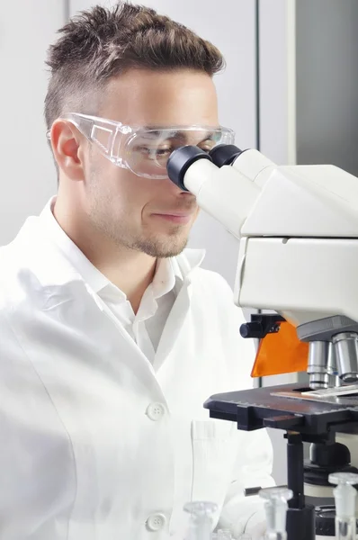 Ilmuwan muda mempelajari substansi baru atau virus dalam mikroskop — Stok Foto