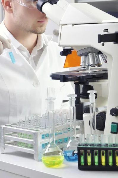 Young scientist studying new substance or virus in microscope — Stock Photo, Image