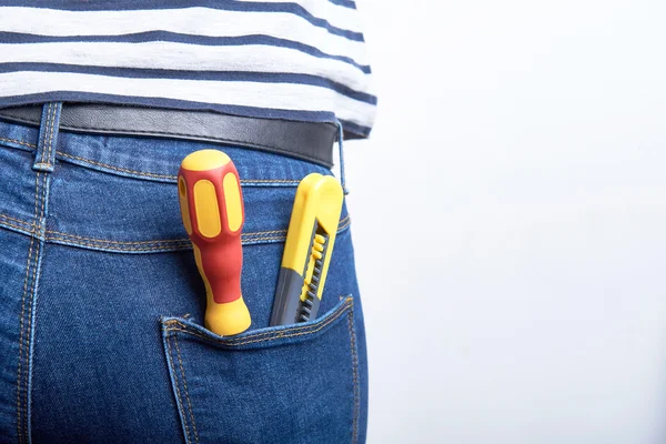 Инструменты для электрика в заднем кармане синих джинсов, которые носит женщина. Отвёртка и острый нож . — стоковое фото