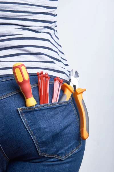 Attrezzi per elettricista in tasca posteriore di blue jeans indossati da una donna. Cacciavite, taglierine e poche fascette . — Foto Stock