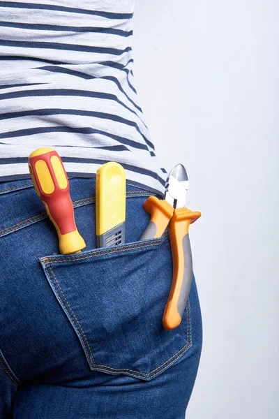 Outillage pour électricien dans la poche arrière de jeans bleus portés par une femme. Tournevis, pinces coupées et couteau tranchant . — Photo