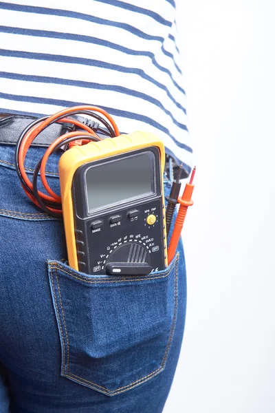 Elektronik multimeter untuk listrik di saku belakang jeans biru dikenakan oleh seorang wanita . — Stok Foto