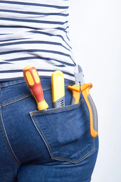 Attrezzi per elettricista in tasca posteriore di blue jeans indossati da una donna. Cacciavite, coltello affilato e frese . — Foto Stock