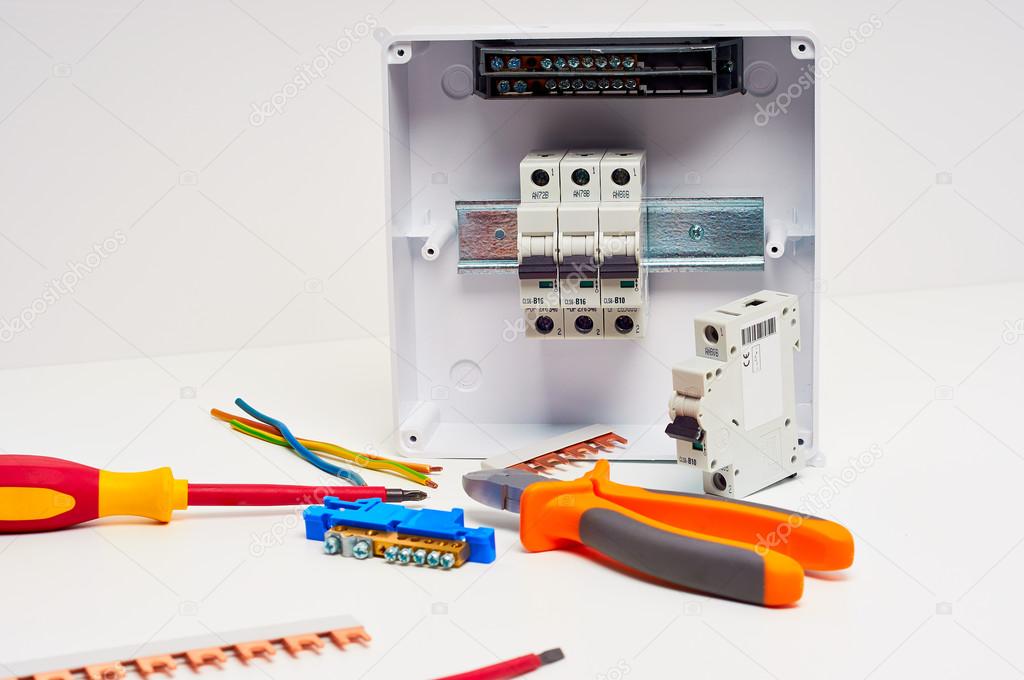Fusebox with four automatic fuses during installation. Electricity distribution box. Electrical cabinet with tools.