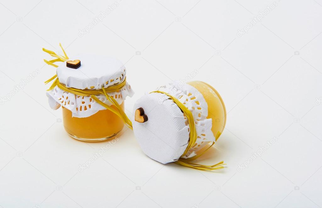 Golden honey in small jar on white background