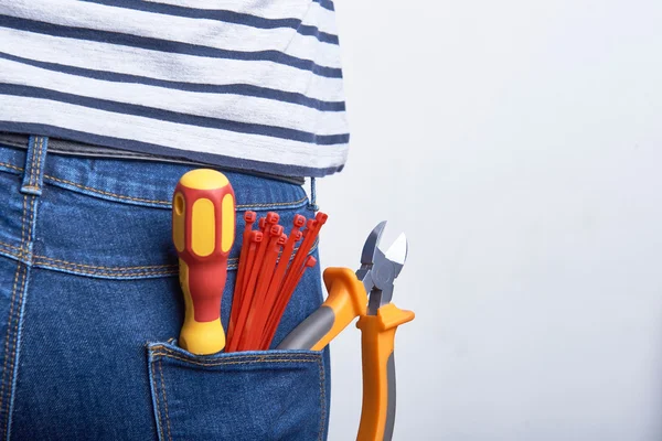 Outillage pour électricien dans la poche arrière de jeans bleus portés par une femme. Tournevis, fraises et fermetures éclair . — Photo