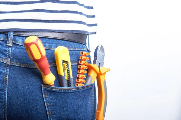 Outillage pour électricien dans la poche arrière de jeans bleus portés par une femme. Tournevis, couteau tranchant, fraises et connecteurs . — Photo