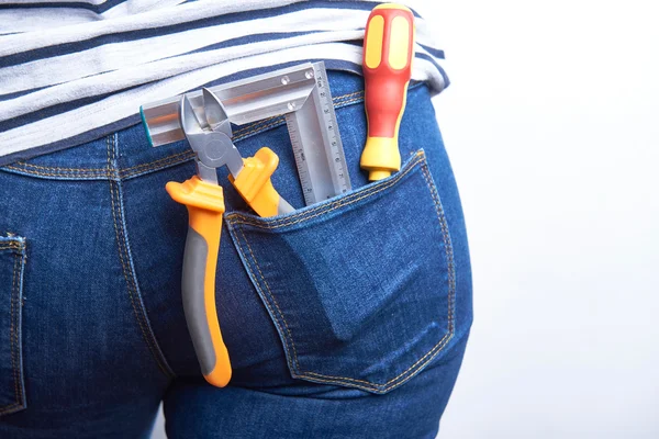 Outillage pour électricien dans la poche arrière de jeans bleus portés par une femme. Tournevis, fraises et support . — Photo