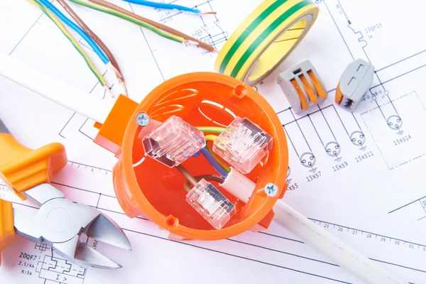 Metalen snijtang, isolatietape en aangesloten kabel in elektrische aansluitdoos, liggend op elektrische diagrammen. Werktuigen voor ingenieurswerk, concept van elektrische werken. — Stockfoto